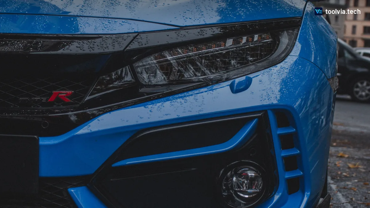 Close-up of a blue Honda Civic Type R front bumper and headlight with rain drops